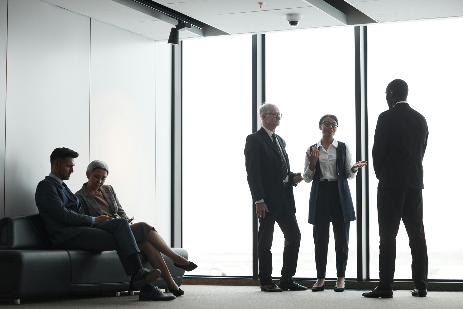 Advisors in quiet conversation beside floor-to-ceiling windows